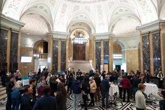 Wide view of the audience socialising in the entrance hall after the event