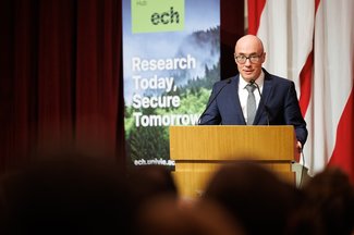 Nikolaus Hautsch addressing the audience from the podium, with an ECH banner in the background