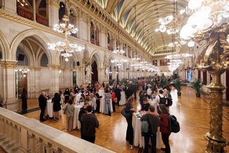 View of the ballrom of Vienna City Hall during the standing reception after the event, with small groups of people standing around desks and talking