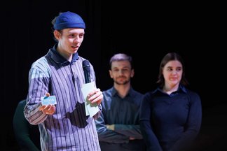 A teammate presenting the team's idea on the stage, with two other people in the background