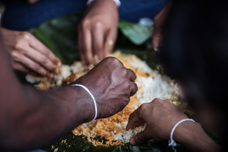People eating a rice dish with their hands
