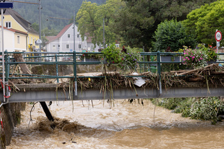 Bild einer Brücke in Österreich mit einem überschwemmten, braunen Fluss darunter