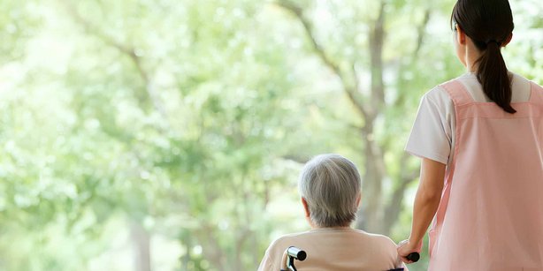 Caregiver and senior woman in a wheelchair looking out the window at nature.