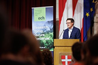Jürgen Czernohorszky on the podium addressing the audience, with an ECH banner in the background
