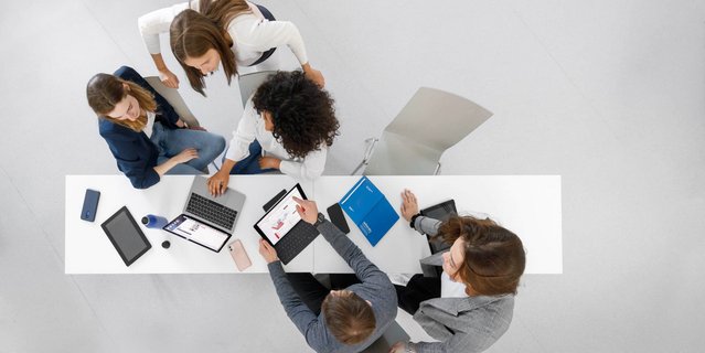 Top-down view of a group of people around a desk discussing with each other