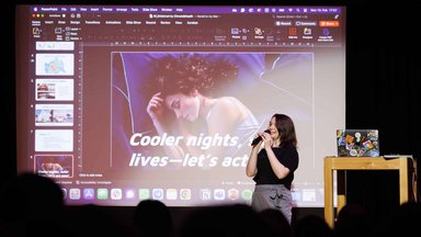 Teammate presenting their team's idea on the stage with the presentation in the background