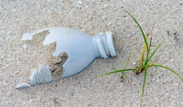 shattered plastic bottle laying in sand 