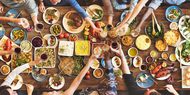 View of a table with different dishes from above and human hands sharing the food