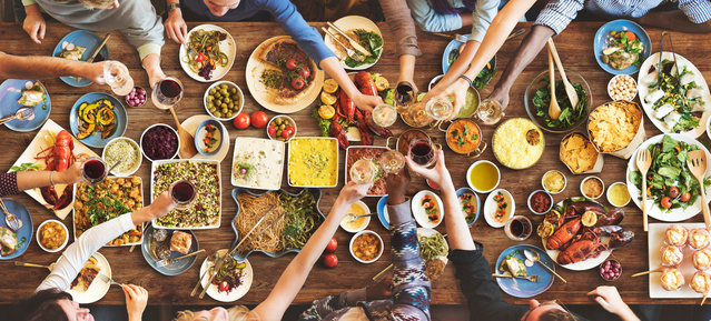 View of a table with different dishes from above and human hands sharing the food