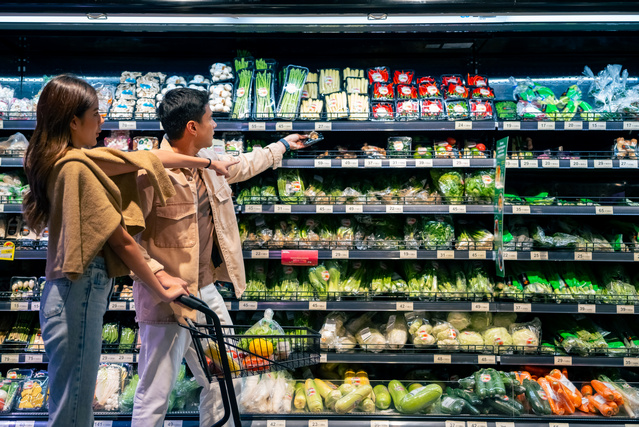 A couple in front of a produce shelf in a supermarket choosing between the different options