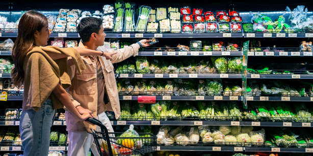 A couple in front of a produce shelf in a supermarket choosing between the different options