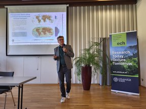 Andreas Stohl giving a flash talk with his presentation in the background and a banner with the ECH logo standing next to him.