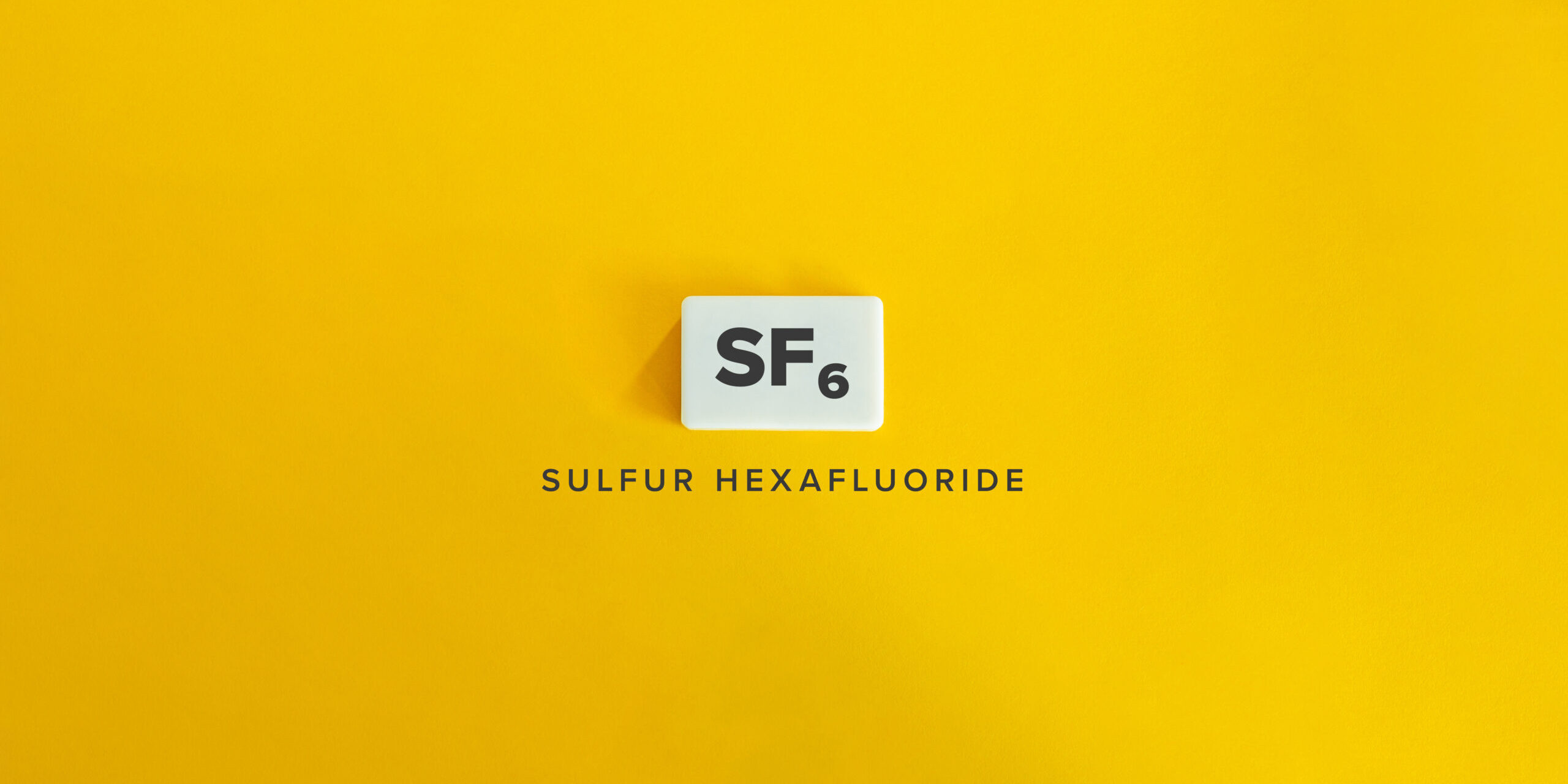 Sulfur Hexafluoride (SF₆). Greenhouse Gas (GHG). Text on Block Letter Tile on Yellow Background. Minimalist Aesthetics.